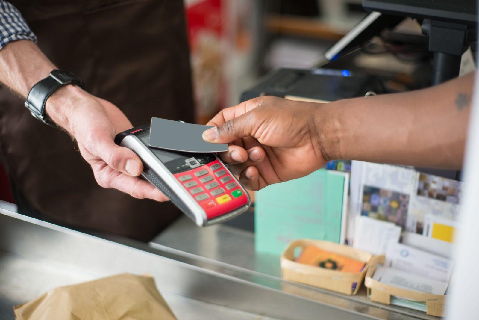 Un cliente acerca su tarjeta a un POS que sostiene el vendedor